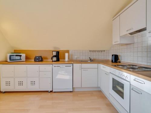 a kitchen with white cabinets and white appliances at Apartment in Westerwald with private balcony 