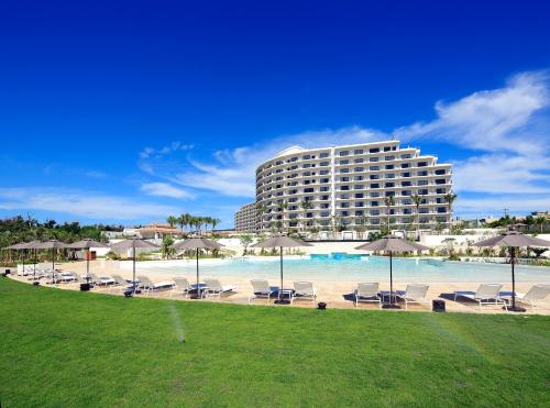 a hotel with chairs and umbrellas and a pool at Hotel Monterey Okinawa Spa & Resort in Onna