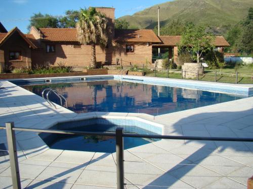 a swimming pool in front of a house at Cabañas El Eden Spa in La Falda