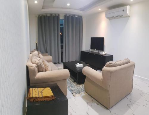 a living room with two chairs and a television at Durrat Alkhuwair Hotel Apartment درة الخوير للشقق الفندقية in Muscat