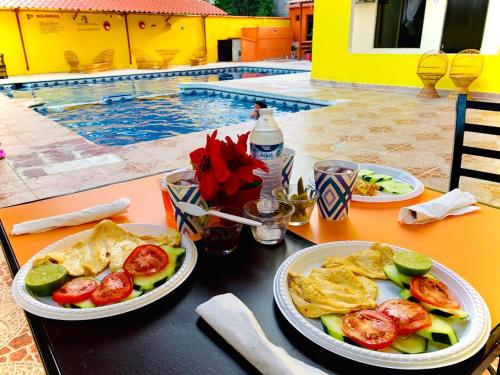 a table with two plates of food on a table near a pool at Hotel Sociedad y Maristas in Tecolutla