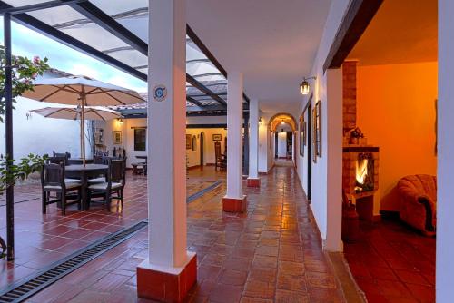 een woonkamer met een tafel en stoelen en een open haard bij Hotel Don Paulino in Villa de Leyva