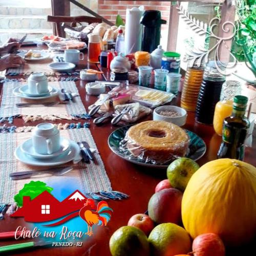 a table with food and fruit on top of it at Pousada Chalé na Roça Penedo in Penedo