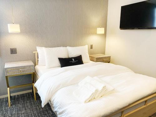 a hotel room with a large white bed and a television at The Barn Tokyo in Tokyo