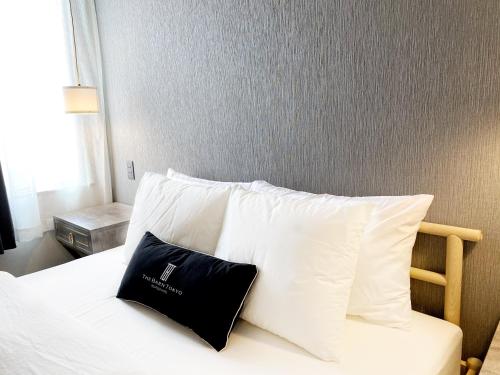 a bed with white pillows and a black pillow on it at The Barn Tokyo in Tokyo