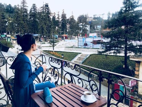 a woman sitting at a table on a balcony at Sapa Centre Hotel in Sa Pa