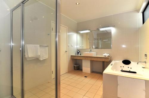 a bathroom with a shower and a sink and a mirror at Mission Beach Resort in Mission Beach