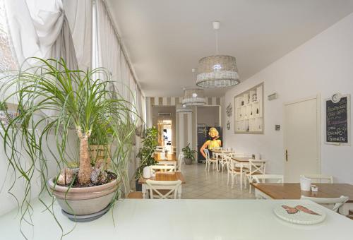 a woman sitting at a table with a potted plant at City Hotel in Viareggio