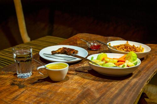 un tavolo con piatti di cibo e una ciotola di insalata di Yala Dream Park a Yala