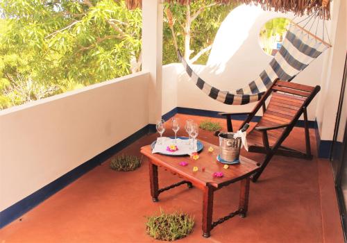 a table and chair on a balcony with a hammock at Le Grand Bleu in Andilana