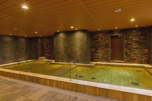 a jacuzzi tub in a room with a stone wall at Hot Spring Osaka Hinode Hotel Nipponbashi in Osaka