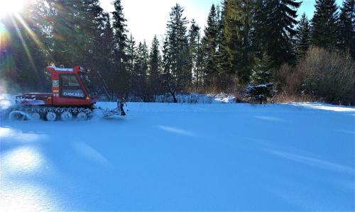 a red tractor driving through a snow covered field at Apartmán Elenka in Zuberec