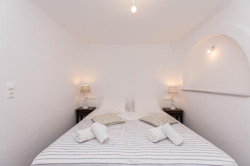 a white bedroom with a bed with two pillows at Peristeronas Village in Klouvas
