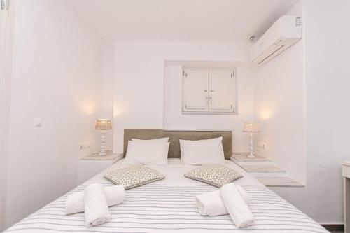 a white bedroom with a large white bed with pillows at Peristeronas Village in Klouvas