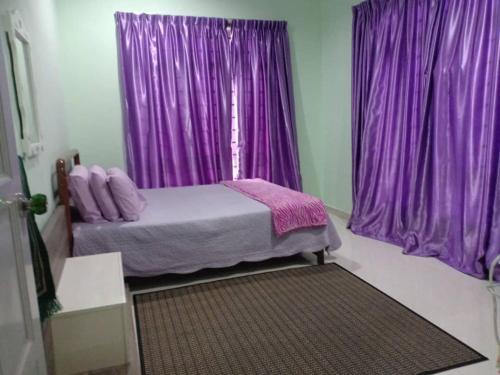 a bedroom with purple curtains and a bed with a window at Sofea Homestay in Batu Rakit