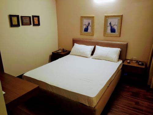 a bedroom with a bed with white sheets and paintings on the wall at Independent Charming Studio with balcony Urban view in Noida