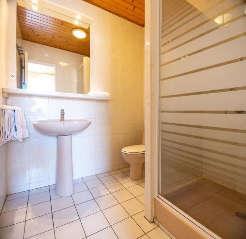 La salle de bains est pourvue d'un lavabo, de toilettes et d'une douche. dans l'établissement Contact HOTEL LES TERRASSES, au Le Verdon-sur-Mer