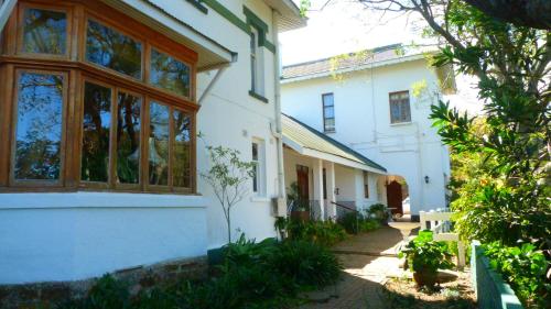 a white building with windows and a pathway at Royston Hall Historical Guesthouse in Umtentweni