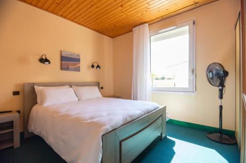 Schlafzimmer mit einem Bett, einem Fenster und einem Ventilator in der Unterkunft Contact HOTEL LES TERRASSES in Le Verdon-sur-Mer