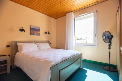 a bedroom with a bed with a window and a fan at Hôtel LES TERRASSES in Le Verdon-sur-Mer