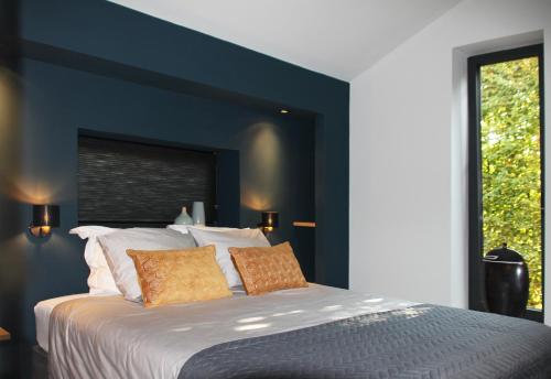 una camera da letto con un letto grande con una parete blu di Hoeve Altena Cottage a Woudrichem