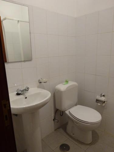 a white bathroom with a toilet and a sink at Hospedaria Lampião in Penacova