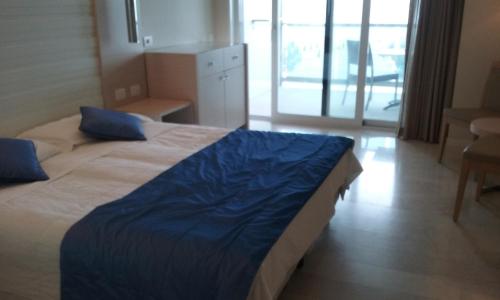 a hotel room with a bed with a blue blanket at Hotel Columbus in Lignano Sabbiadoro