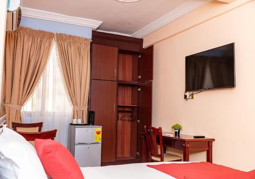 a bedroom with a bed and a desk and a television at SWEET PEE EXECUTIVE HOTEL in Ayeduasi
