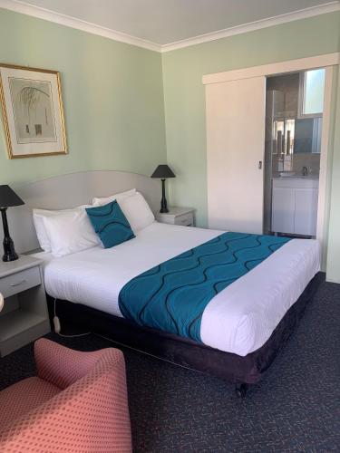 a bedroom with a large bed and a chair at High Mountains Motor Inn in Blackheath