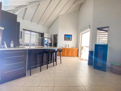 a kitchen with blue cabinets and bar stools at La villa de Christian in Baie-Mahault