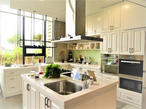 a kitchen with white cabinets and a stainless steel sink at Villa Le Ballon Bleu in Wujie