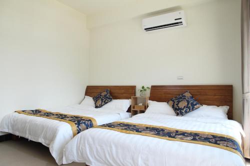 two beds in a room with white walls at Ancient Official Road Homestay in Jinhu