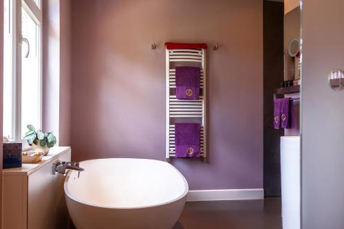 a bathroom with a white tub and purple walls at B&B Saint-Georges -Located in the city centre of Bruges- in Bruges
