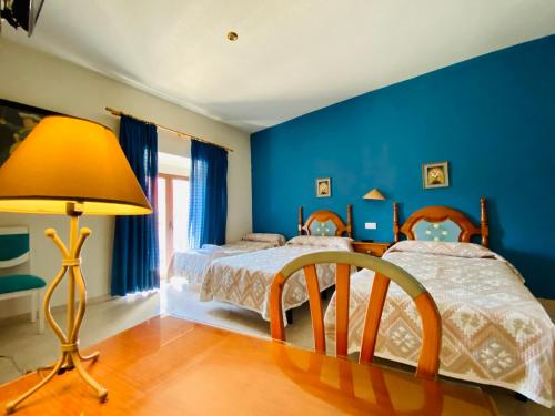Dormitorio azul con 2 camas y lámpara en Hostal León, en Trujillo