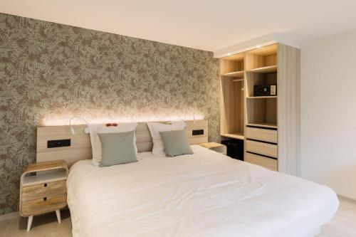 a bedroom with a large white bed with a wall at Beach Hotel Helios by CW Hotel Collection in Blankenberge
