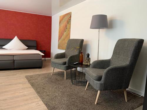 2 Stühle und ein Tisch in einem Zimmer mit einem Bett in der Unterkunft Hotel und Apartment Garni Eurode Live in Herzogenrath