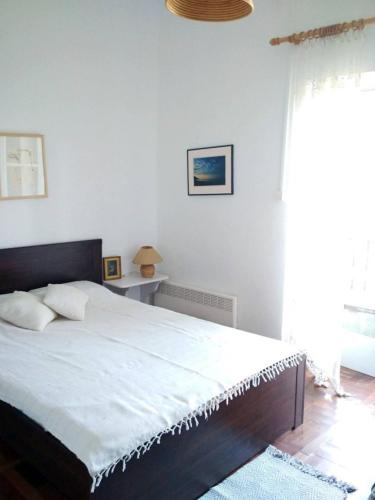 a bedroom with a bed with white sheets and a window at Beach House in Zagora