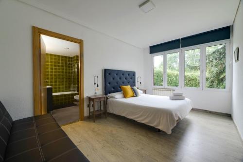 a bedroom with a large bed and a bathroom at Menditxo Eder Rooms in San Sebastián