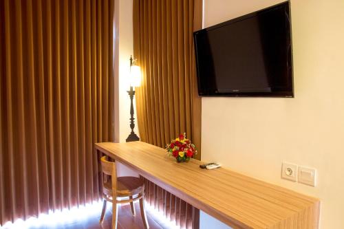 a hotel room with a desk with a television on the wall at DeMira Hotel in Surabaya