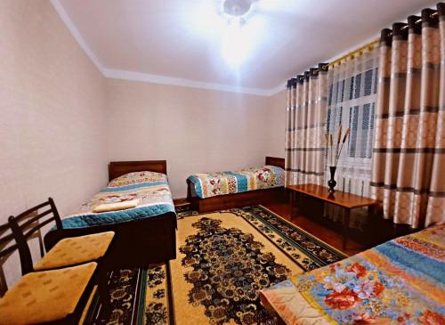 努庫斯的住宿－NUKUS GUEST HOUSE，一间卧室配有两张床、一张桌子和一张地毯。