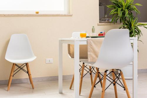 Twee witte stoelen naast een tafel in een keuken. bij Samira in San Vito lo Capo