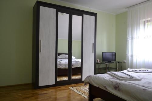 a bedroom with a large glass closet with a bed at Pensiunea Malinul in Bîrsana