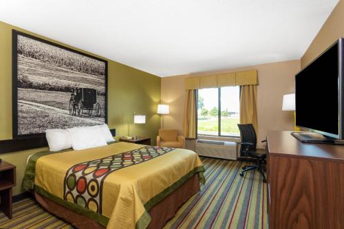 a hotel room with a bed and a flat screen tv at Super 8 by Wyndham Goshen in Goshen