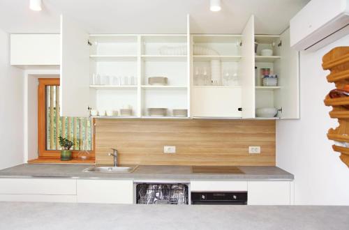 una cocina con armarios blancos y fregadero en Apartment Jurijana - New 4-Bedroom Triplex with Sauna & Garden, en Bohinj