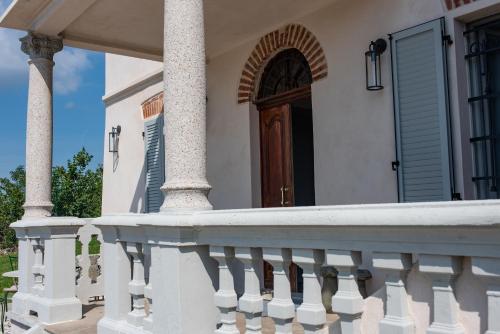 a white house with a porch with a wooden door at Theresa sulla Collina in Passerano 