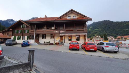 维尔德斯韦尔Gasthof Hirschen in Wilderswil的前面有汽车停放的建筑