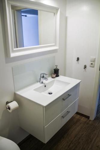 a white bathroom with a sink and a mirror at Alte Käserei Ferienwohnungen in Flensburg