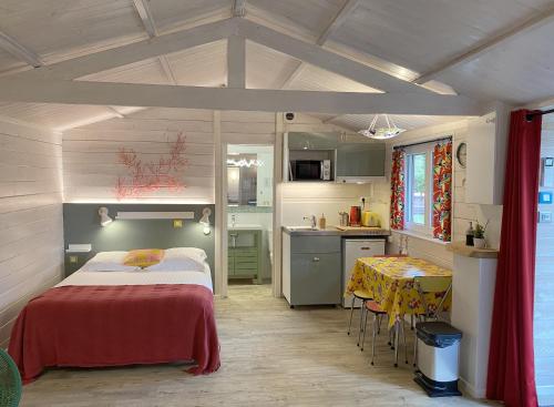 a bedroom with a bed and a kitchen with a table at Le Cabanon de Chessy in Chessy