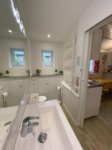 une salle de bain blanche avec un lavabo et un miroir dans l'établissement Le Cabanon de Chessy, à Chessy