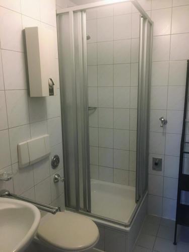 a bathroom with a shower with a toilet and a sink at Airport Park Hotel MUC in Hallbergmoos